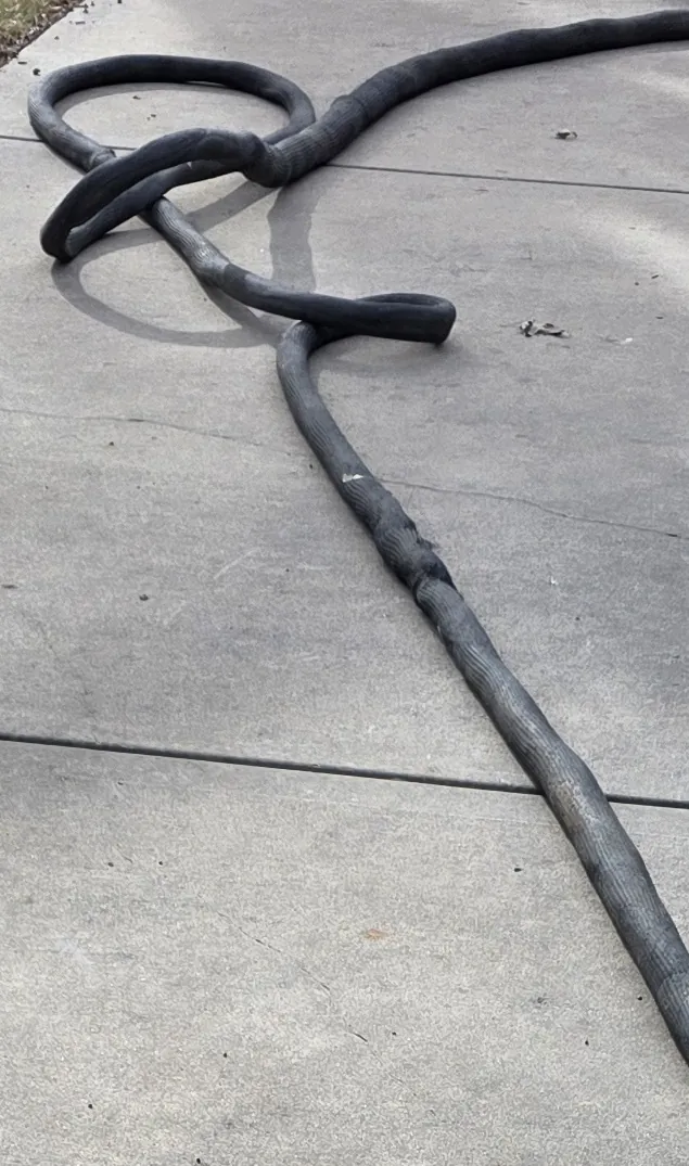 A coiled concrete-leveling injection hose on a residential concrete driveway -- PolyJacks concrete leveling serving Lenexa, KS.